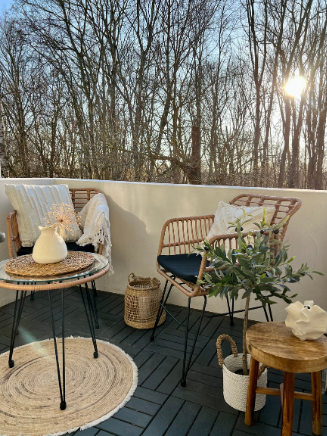 Gem&uuml;tlicher Balkon mit Outdoor-Teppich, Loungesesseln, Beistelltisch und nat&uuml;rlicher Deko aus Holz und Pflanzen