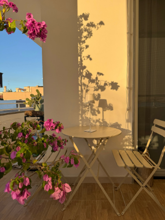 Kleiner Balkon mit Bistro-Set, bl&uuml;henden Pflanzen und warmer Abendstimmung durch Outdoor-Deko