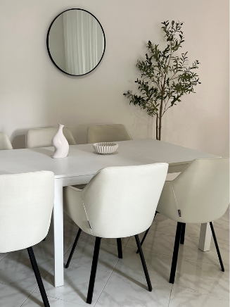 Rechteckiger Esstisch mit wei&szlig;en Esszimmerst&uuml;hlen, rundem Wandspiegel und Zimmerpflanze