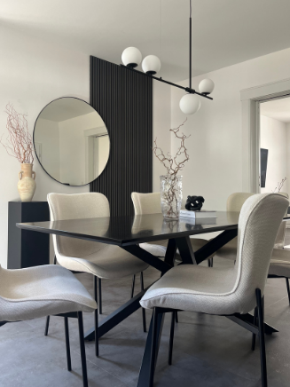 Modernes Esszimmer mit schwarzem Esstisch, hellen Polsterst&uuml;hlen und rundem Wandspiegel im minimalistischen Design.