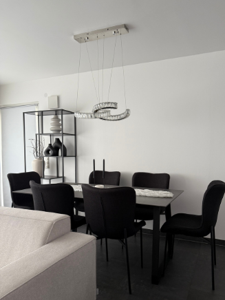 Esszimmer mit schwarzem Esstisch, gepolsterten St&uuml;hlen in Schwarz und moderner Deckenleuchte im eleganten Look.