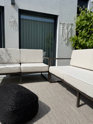 Gem&uuml;tliche Leseecke mit cremefarbenem Sessel, rundem Polsterhocker und dekorativen Vasen im Clean-Living-Stil