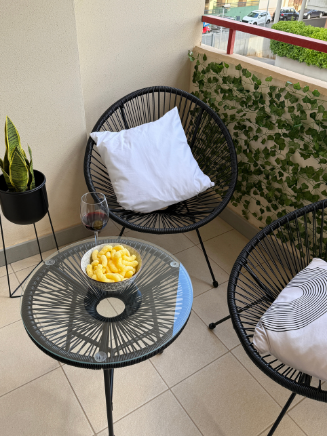 Gem&uuml;tliche Balkon-Ecke mit zwei runden St&uuml;hlen und Glastisch