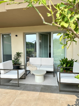 Gemütliche Lounge auf überdachter Terrasse Überdachte Terrasse mit Outdoor-Sofa, Beistelltisch und Pflanzen in hellem, modernem Stil.