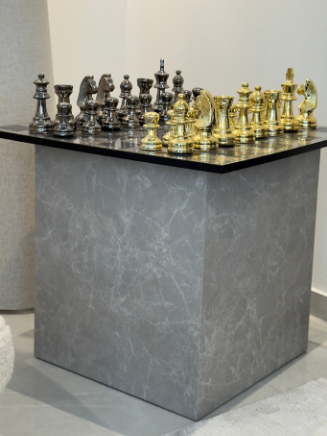 Moderner W&uuml;rfel-Beistelltisch in Steinoptik mit elegantem Schachspiel in Gold und Silber als Blickfang. 