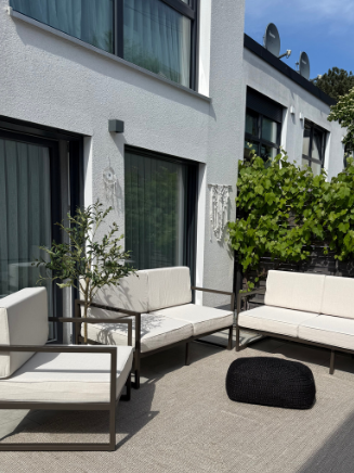 Moderne Terrasse mit Outdoor-Loungem&ouml;beln in Beige und dunklem Gestell vor Hausfassade