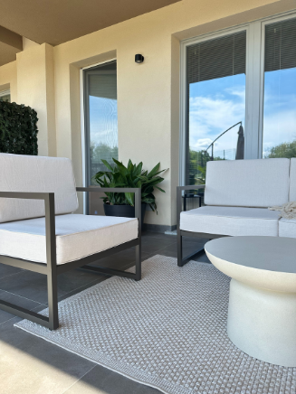 &Uuml;berdachte Terrasse mit Loungesesseln in Beige, kleinem Tisch und Blick auf Terrassent&uuml;r