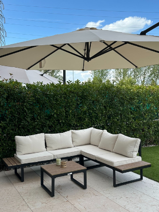Garten-Loungeecke mit beigen Polstern, schwarzen Tischen und gro&szlig;em Sonnenschirm