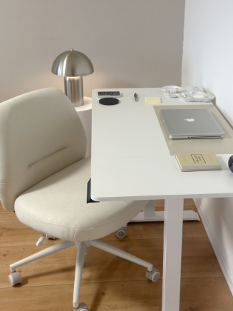 Wei&szlig;er B&uuml;rostuhl mit Polsterung an einem Schreibtisch mit Laptop und Lampe