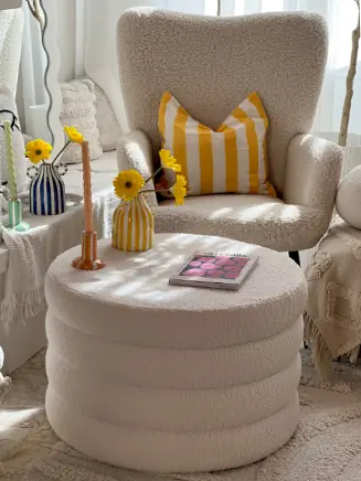 Gem&uuml;tliche Leseecke mit cremefarbenem Sessel, rundem Polsterhocker und dekorativen Vasen im Clean-Living-Stil