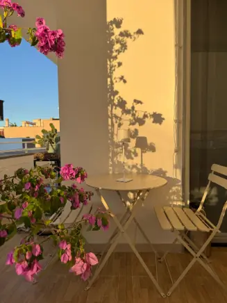 Kleiner Balkon mit Bistro-Set, bl&uuml;henden Pflanzen und warmer Abendstimmung durch Outdoor-Deko