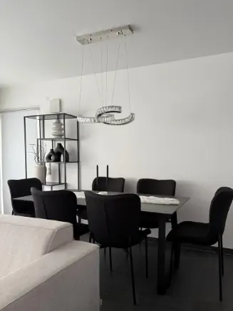 Esszimmer mit schwarzem Esstisch, gepolsterten St&uuml;hlen in Schwarz und moderner Deckenleuchte im eleganten Look.