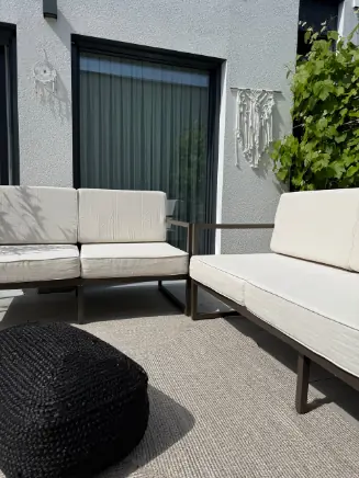 Gem&uuml;tliche Leseecke mit cremefarbenem Sessel, rundem Polsterhocker und dekorativen Vasen im Clean-Living-Stil