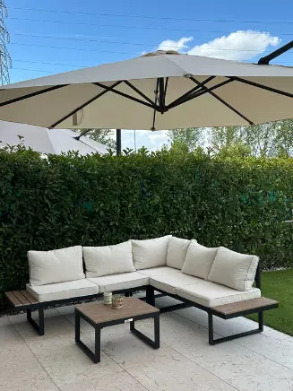 Garten-Loungeecke mit beigen Polstern, schwarzen Tischen und gro&szlig;em Sonnenschirm