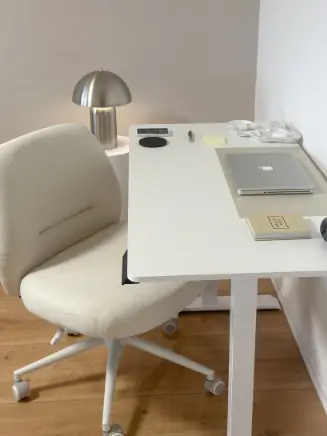 Wei&szlig;er B&uuml;rostuhl mit Polsterung an einem Schreibtisch mit Laptop und Lampe